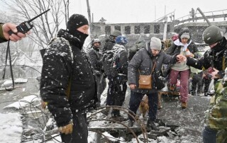 A Ukrainian soldier helps an elderly woman to cross a destroyed bridge during the evacuation by civilians of the city of Irpin, northwest of Kyiv, on March 8, 2022. (Photo by Sergei SUPINSKY / AFP)